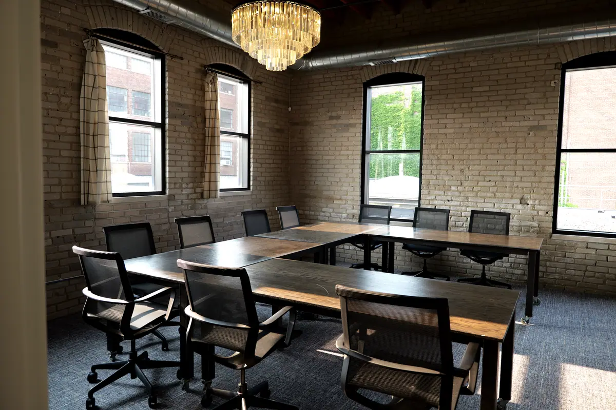 U-shaped conference table under a crystal chandelier with arched windows