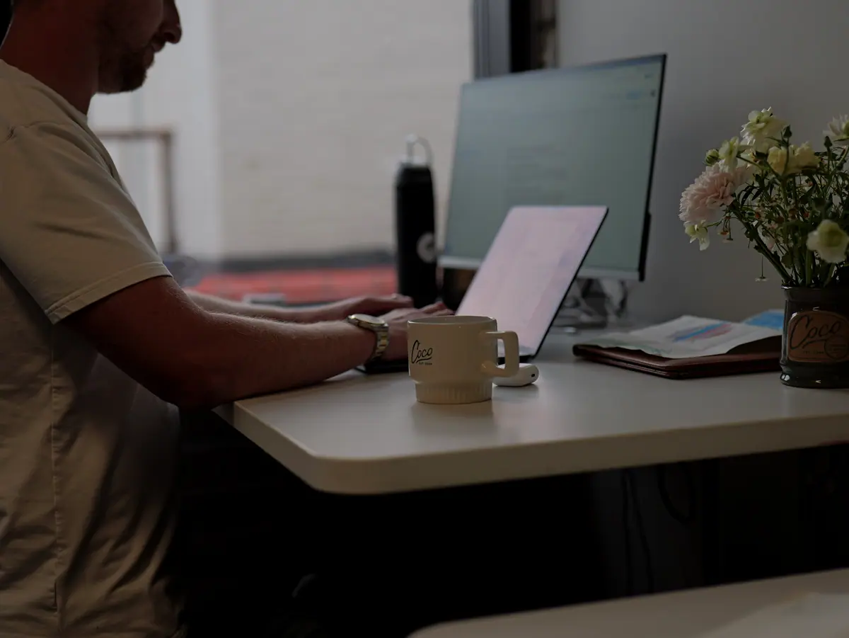 Backlit man working at a desk with flowers