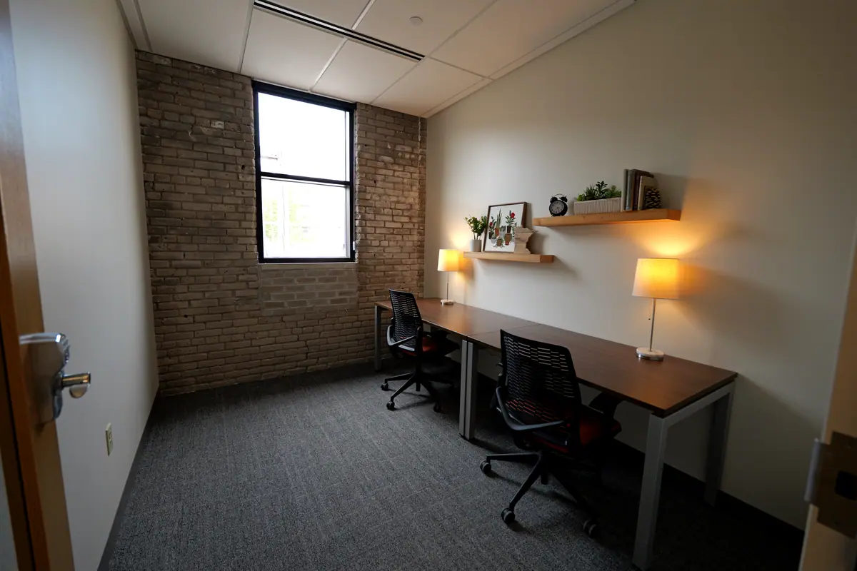 Private office with brick walls, warm table lamps and two workstations
