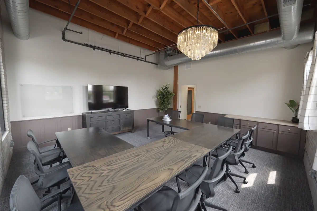 Large boardroom with a crystal chandelier, long wood table and a wall-mounted display